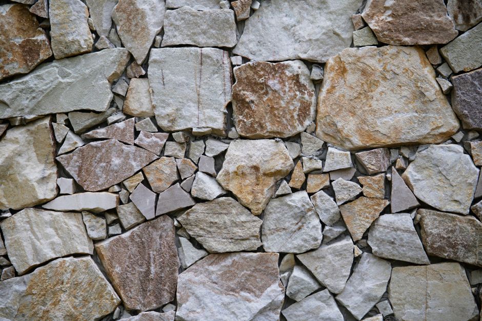Mur de pierres naturelles irrégulières beiges et grises en gros plan