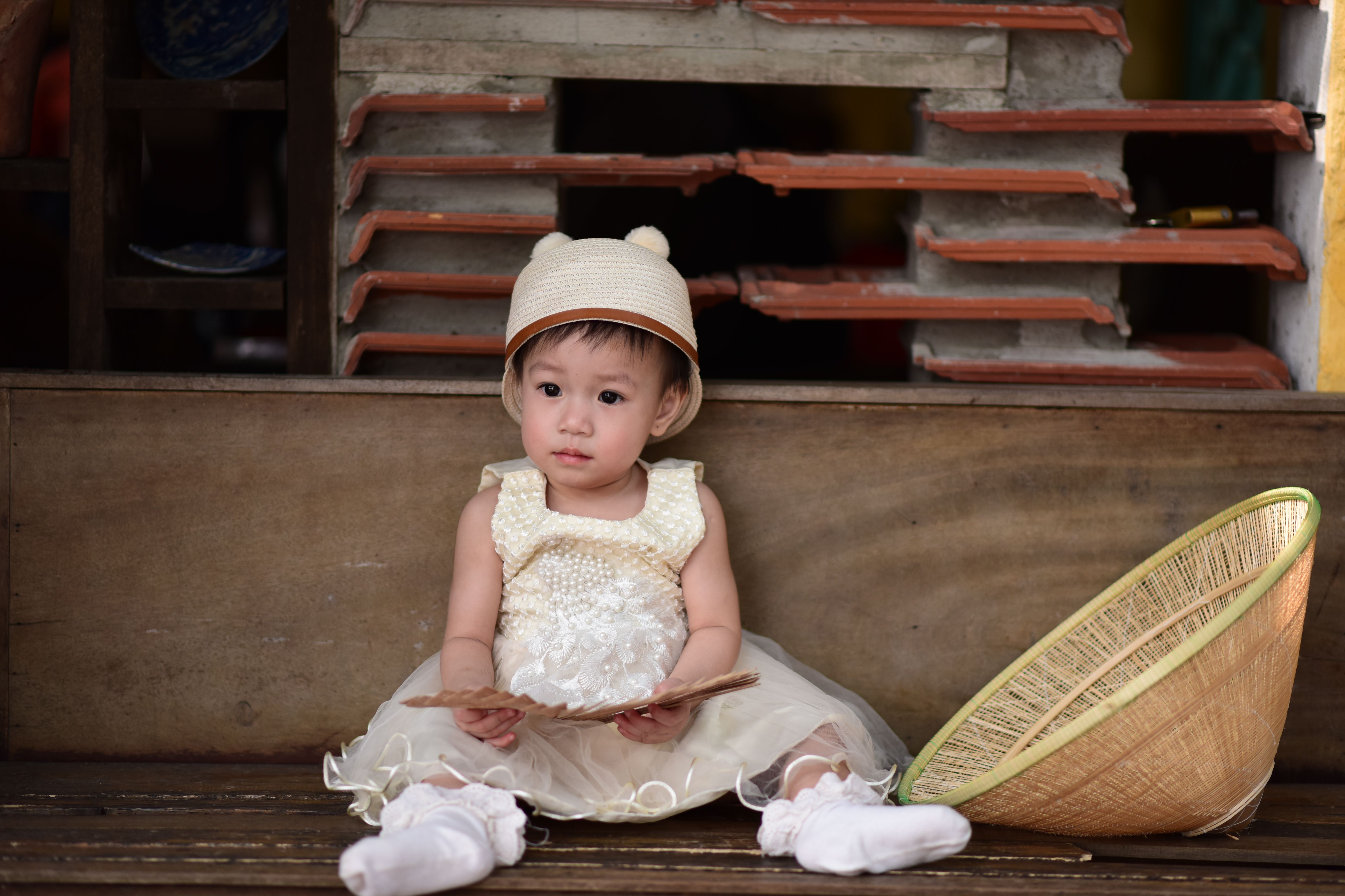 Adorable baby in a cute dress and hat sitting with a woven basket. Perfect portrait capturing cultural essence.