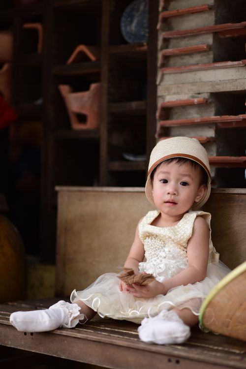 Free Charming young girl wearing vintage dress and hat sitting indoors. Perfect for lifestyle and fashion themes. Stock Photo