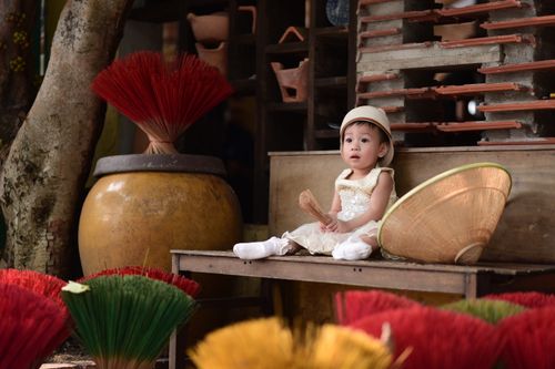 Free A child in a traditional Vietnamese setting surrounded by colorful incense sticks. Stock Photo