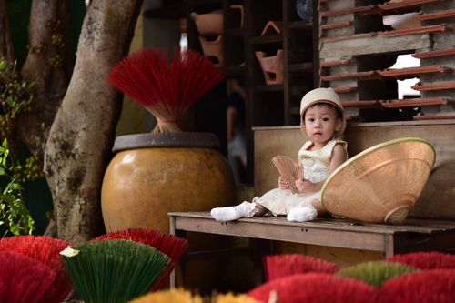 Free Charming child in traditional setting holding incense sticks, surrounded by Vietnamese cultural elements. Stock Photo