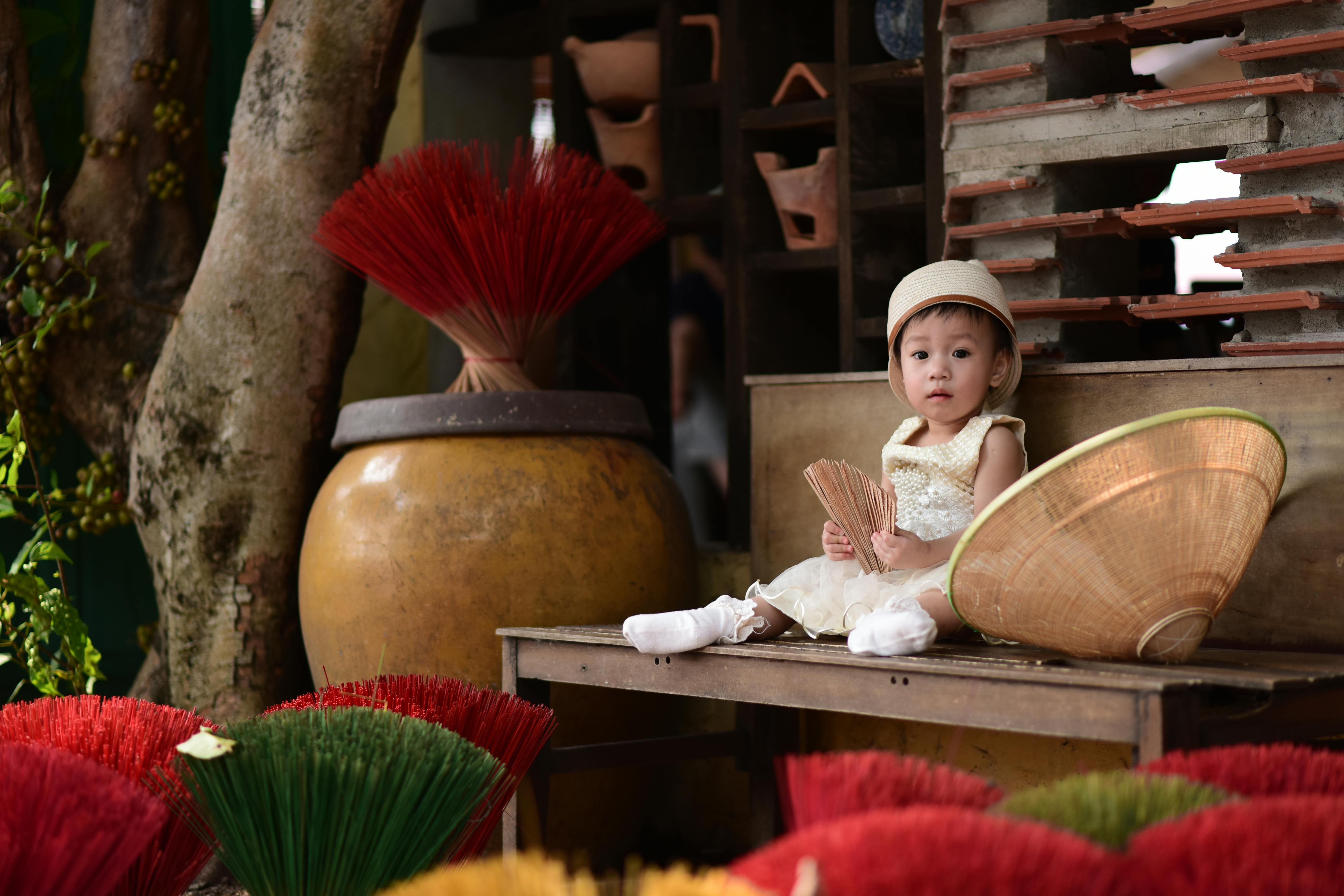 ingyenes Bájos gyermek hagyományos környezetben, füstölőpálcikákkal a kezében, vietnami kulturális elemekkel körülvéve. Stockfotó