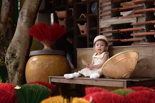Free A cute baby dressed in traditional attire sits surrounded by colorful incense sticks. Stock Photo