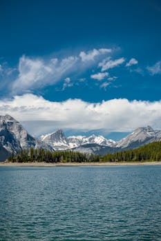 Breathtaking view of the Canadian Rockies with a clear turquoise lake under a bright sky.