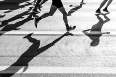 Black and white photo capturing the shadows of runners on a city street during a race.