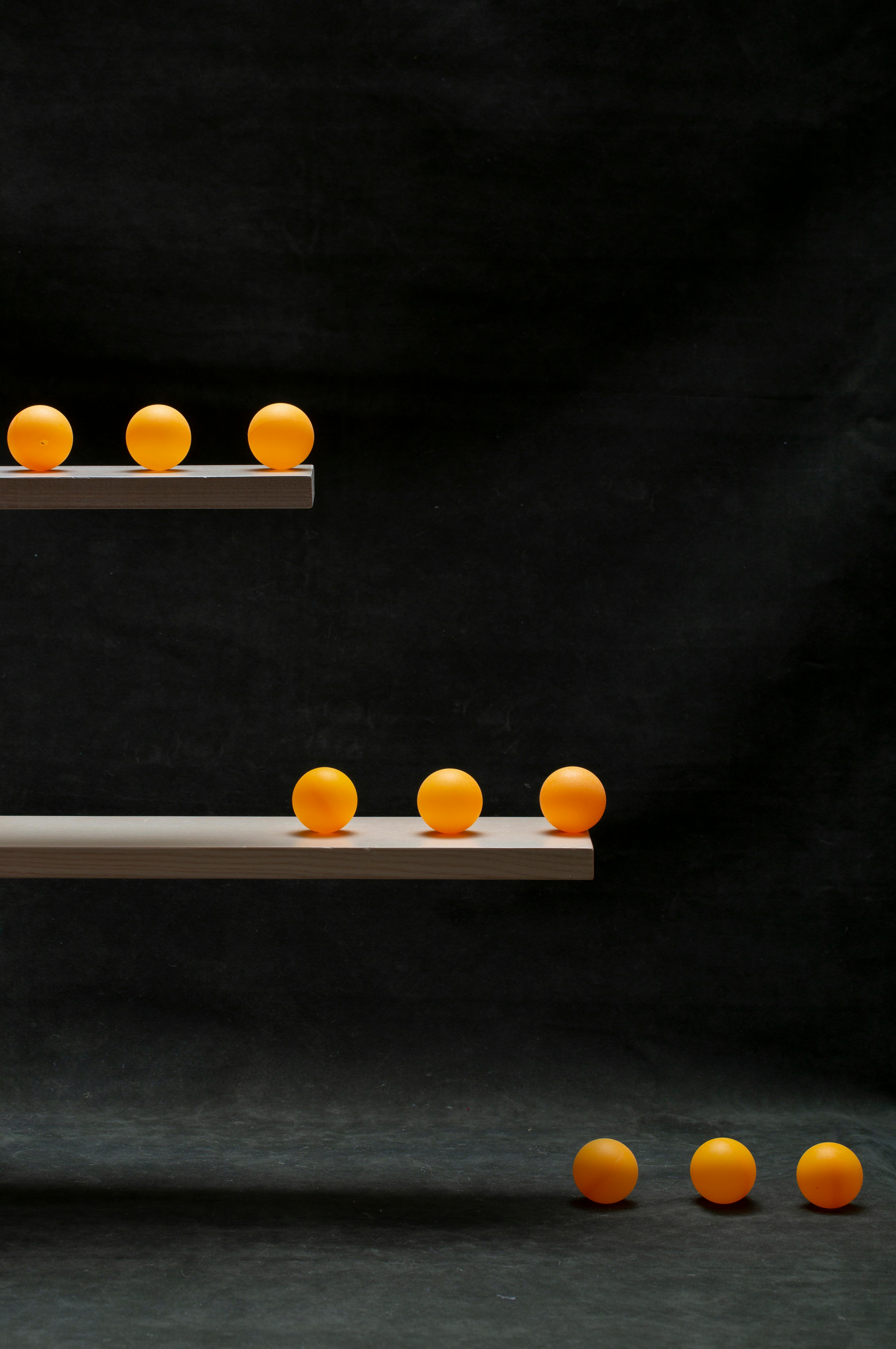 Kostnadsfria Minimalistiskt arrangemang av orange bollar på hyllor med mörk bakgrund, som framhäver färgkontrast. Stock foto