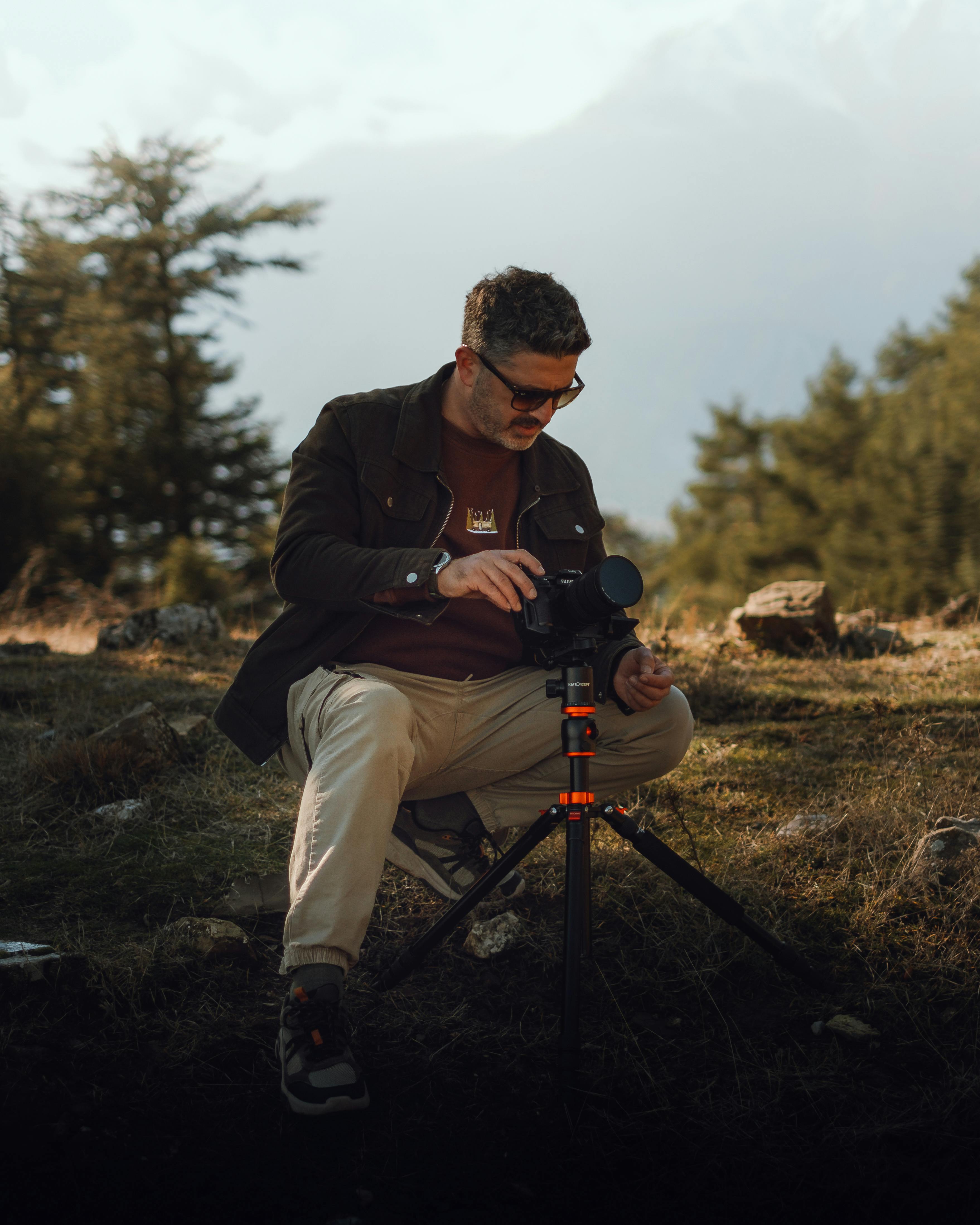 Gratis Uomo che sistema la macchina fotografica sul treppiede in un parco panoramico all'aperto. Foto a disposizione