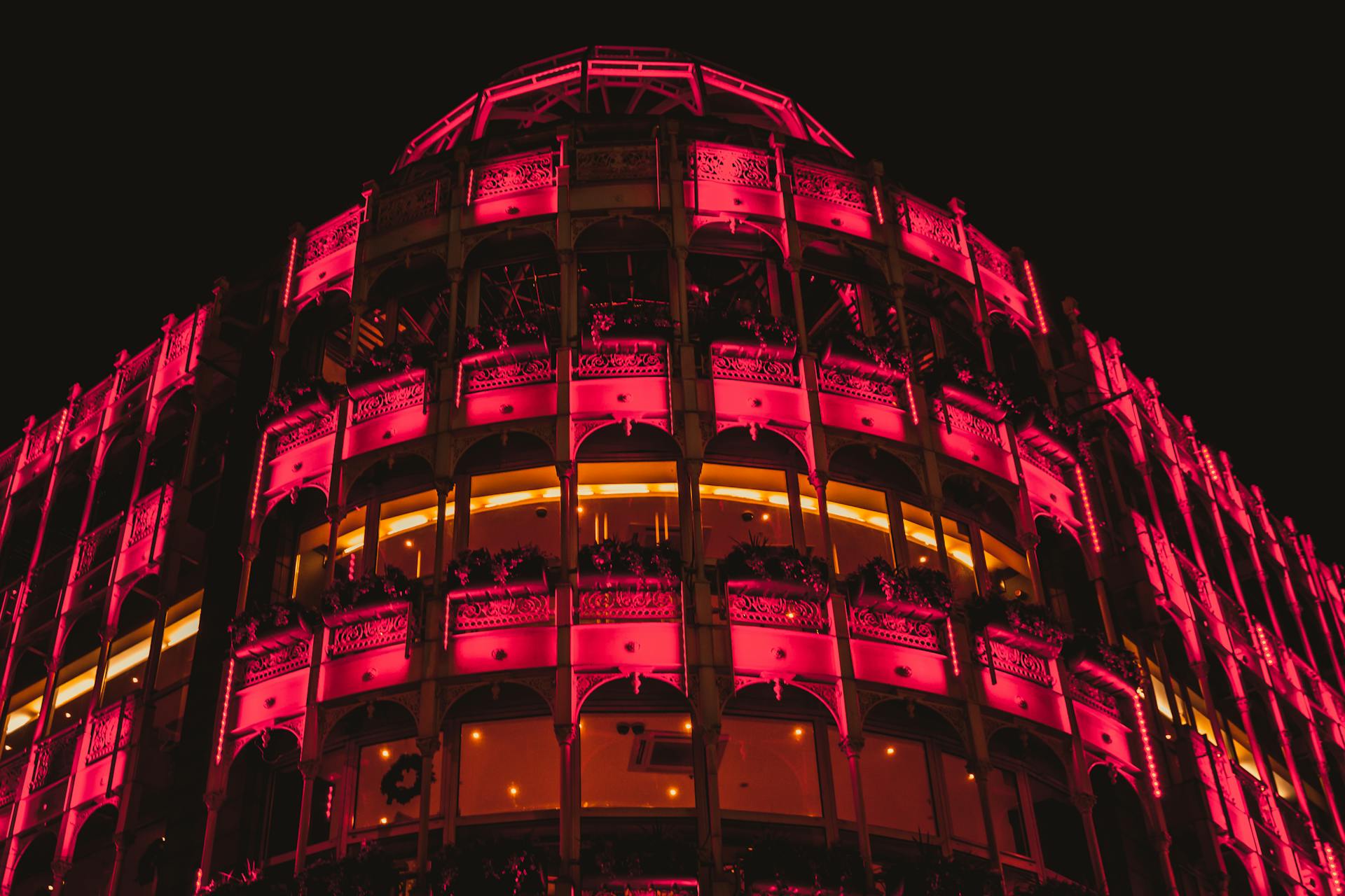 Brightly lit modern building in Dublin, displaying vibrant pink neon lights against the night sky.