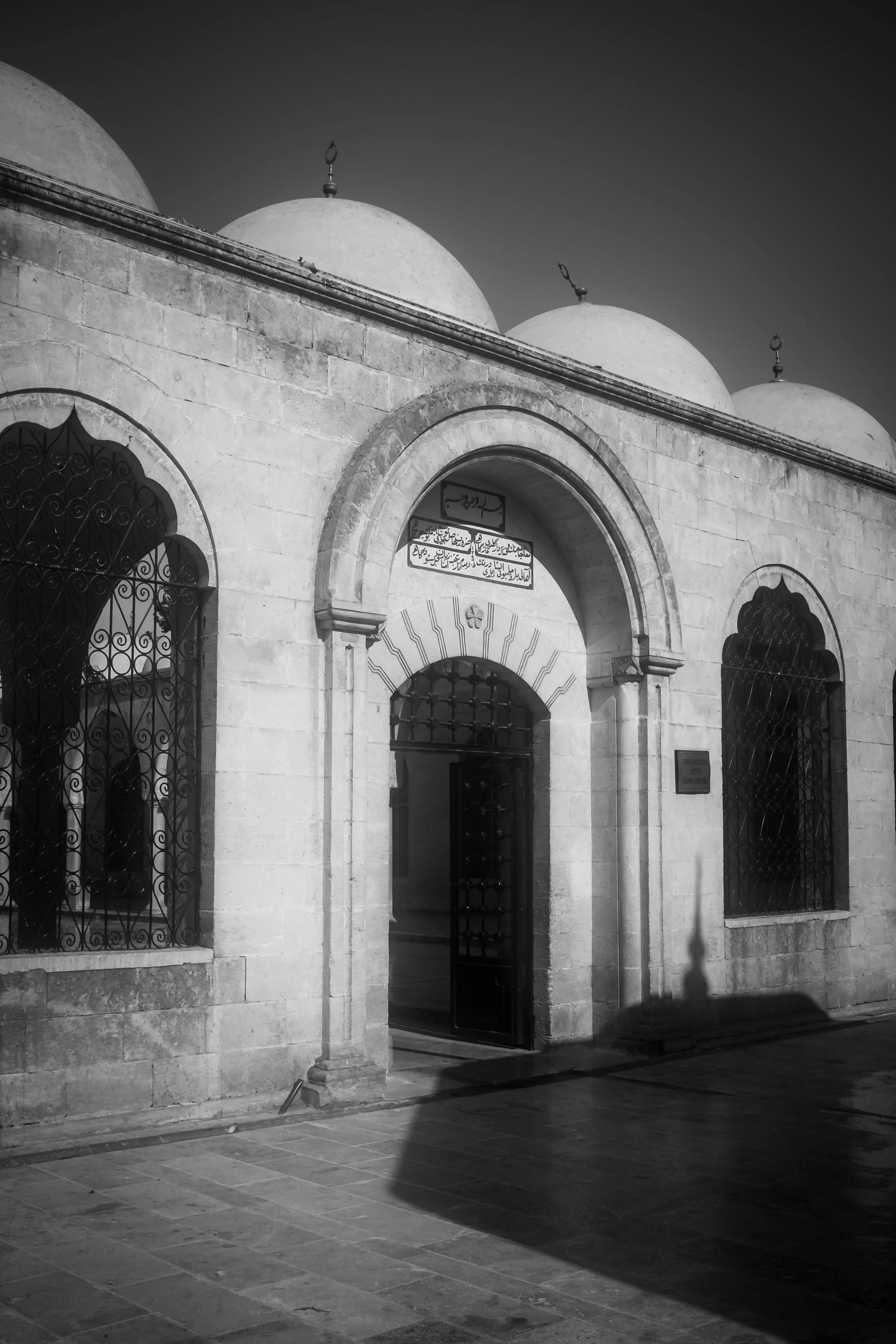 ingyenes Fekete-fehér fotó egy történelmi épületről boltíves ablakokkal és kupolákkal, tiszta ég alatt. Stockfotó