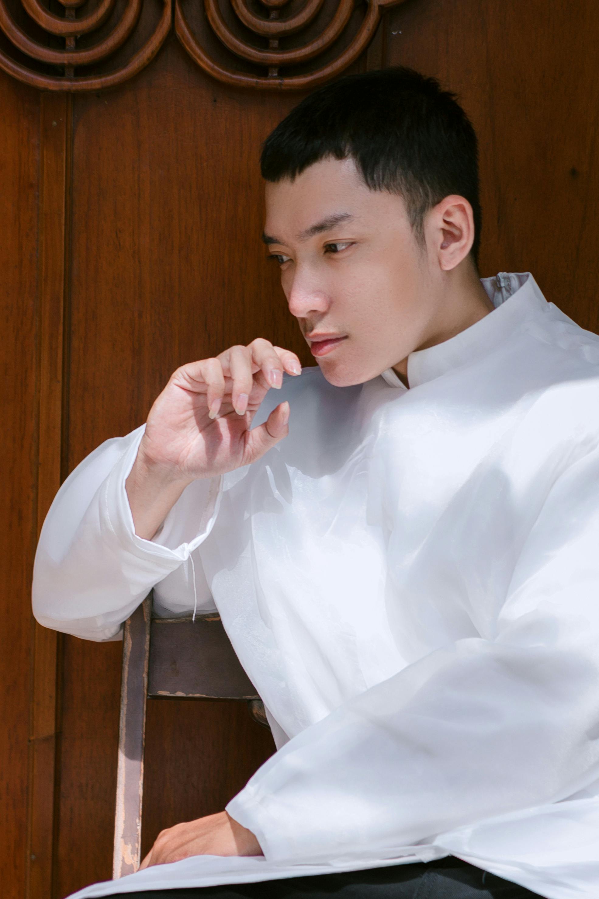 ฟรี ชายครุ่นคิดในเสื้อเชิ้ตสีขาวแบบดั้งเดิม นั่งอยู่ในอาคาร กำลังครุ่นคิดอะไรบางอย่าง คลังภาพถ่าย