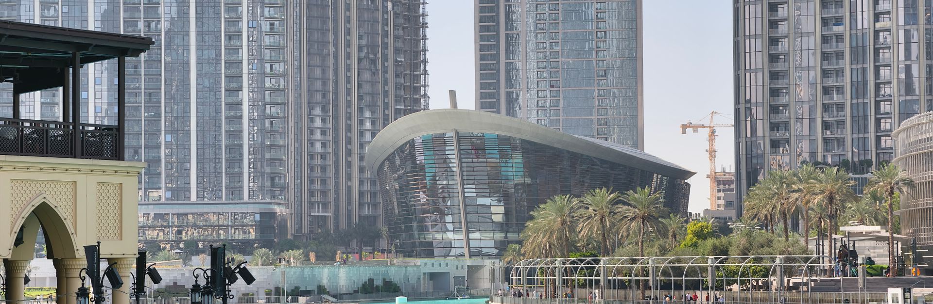 View of Dubai Opera House and surrounding skyscrapers reflecting in the water.