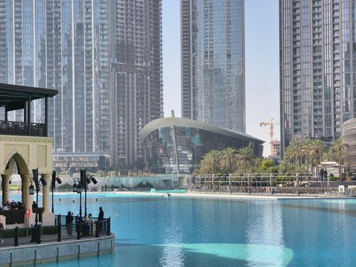 Free View of Dubai Opera House and surrounding skyscrapers reflecting in the water. Stock Photo
