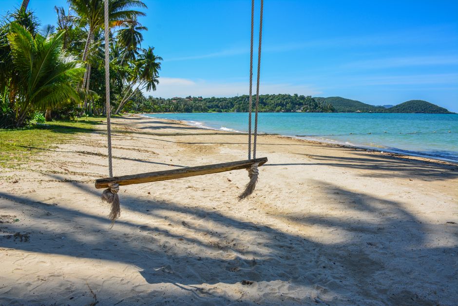 Profite d’une vue sereine d’une plage de sable avec une balançoire sur Ko Mak, Thaïlande, sous un ciel bleu clair.