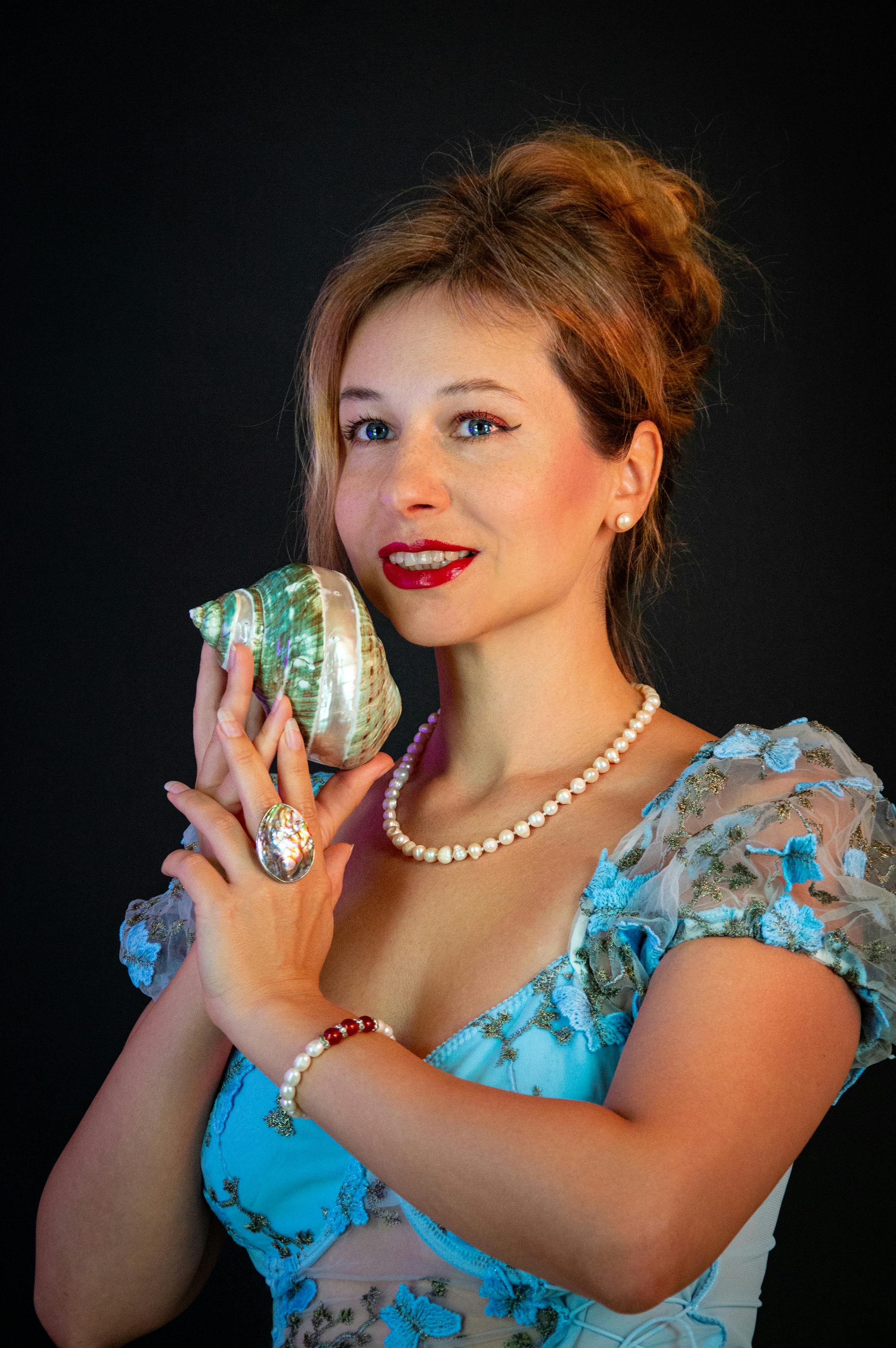 ฟรี หญิงสาวผู้มีเสน่ห์สวมเครื่องประดับไข่มุกถือเปลือกหอย บนพื้นหลังสีดำ คลังภาพถ่าย