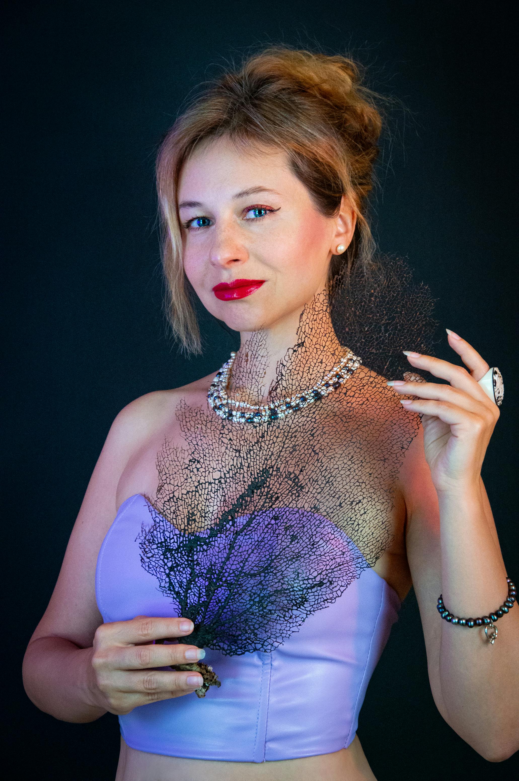 Miễn phí Chân dung một người phụ nữ sành điệu đang cầm một mảnh san hô đen trang trí, toát lên vẻ thanh lịch và tinh tế. Ảnh lưu trữ