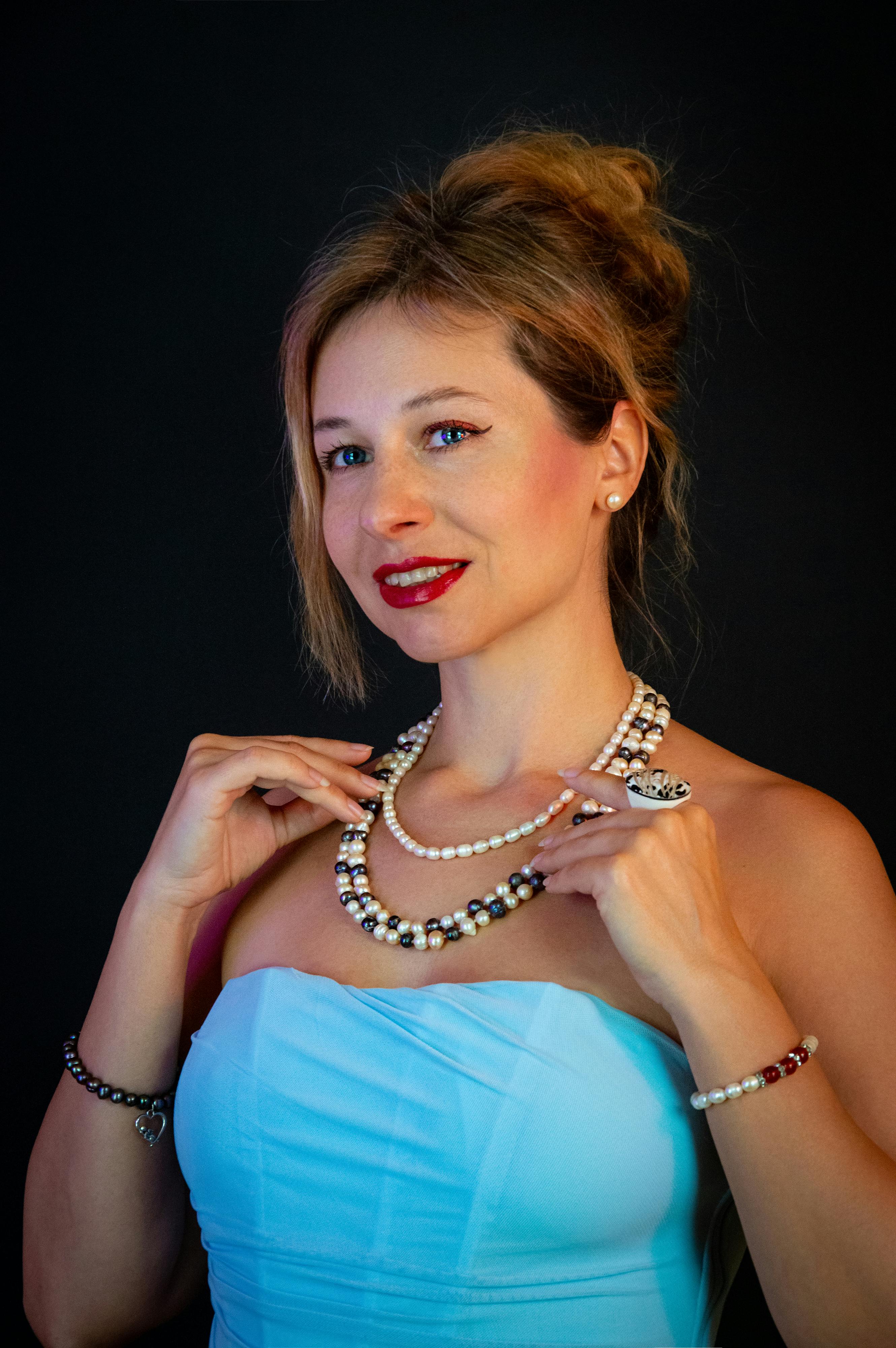 ฟรี ภาพถ่ายหญิงสาวกำลังยิ้ม สวมเครื่องประดับมุกและชุดสีฟ้า โดยมีฉากหลังเป็นสีเข้ม คลังภาพถ่าย