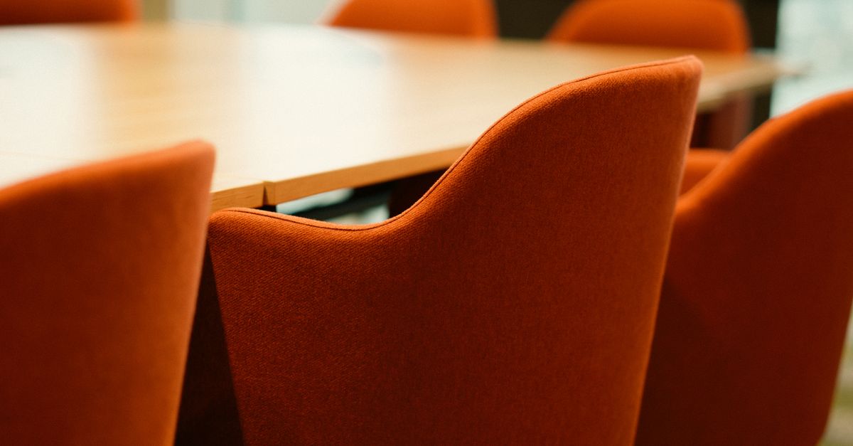 Close-up view of modern orange chairs around a conference table in an office setting.