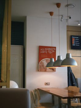 Warmly lit cafe interior with modern pendant lights and minimalist decor, creating a cozy atmosphere.