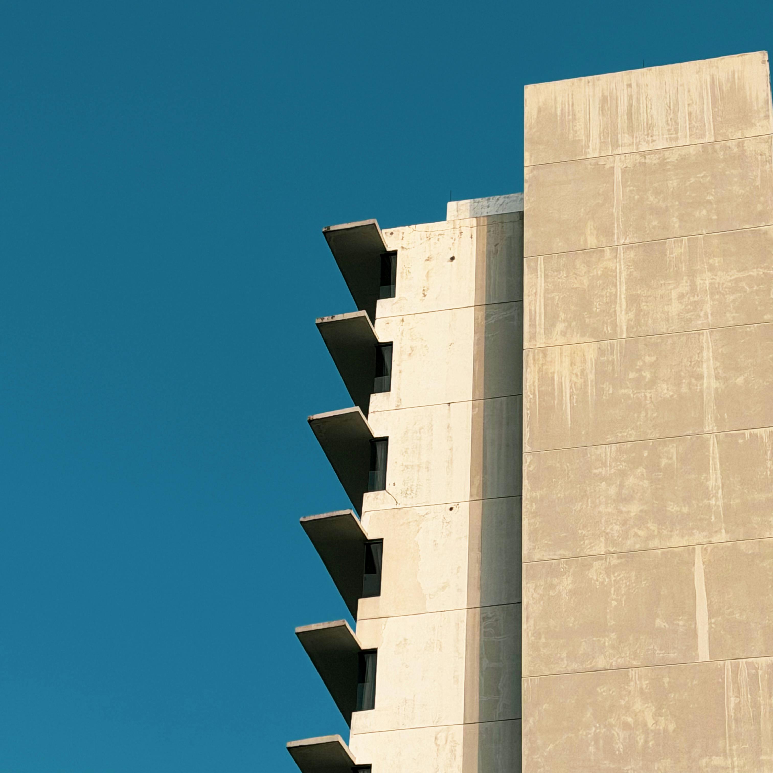 De franc Vista minimalista d'una façana d'edifici modern contra un cel clar, que destaca el disseny arquitectònic. Foto d'estoc