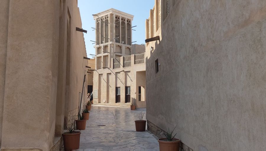 A quiet sand-coloured lane in Al Fahidi with a traditional wind tower at its end