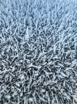 Detailed close-up of frost patterns on a surface, capturing winter's icy textures.