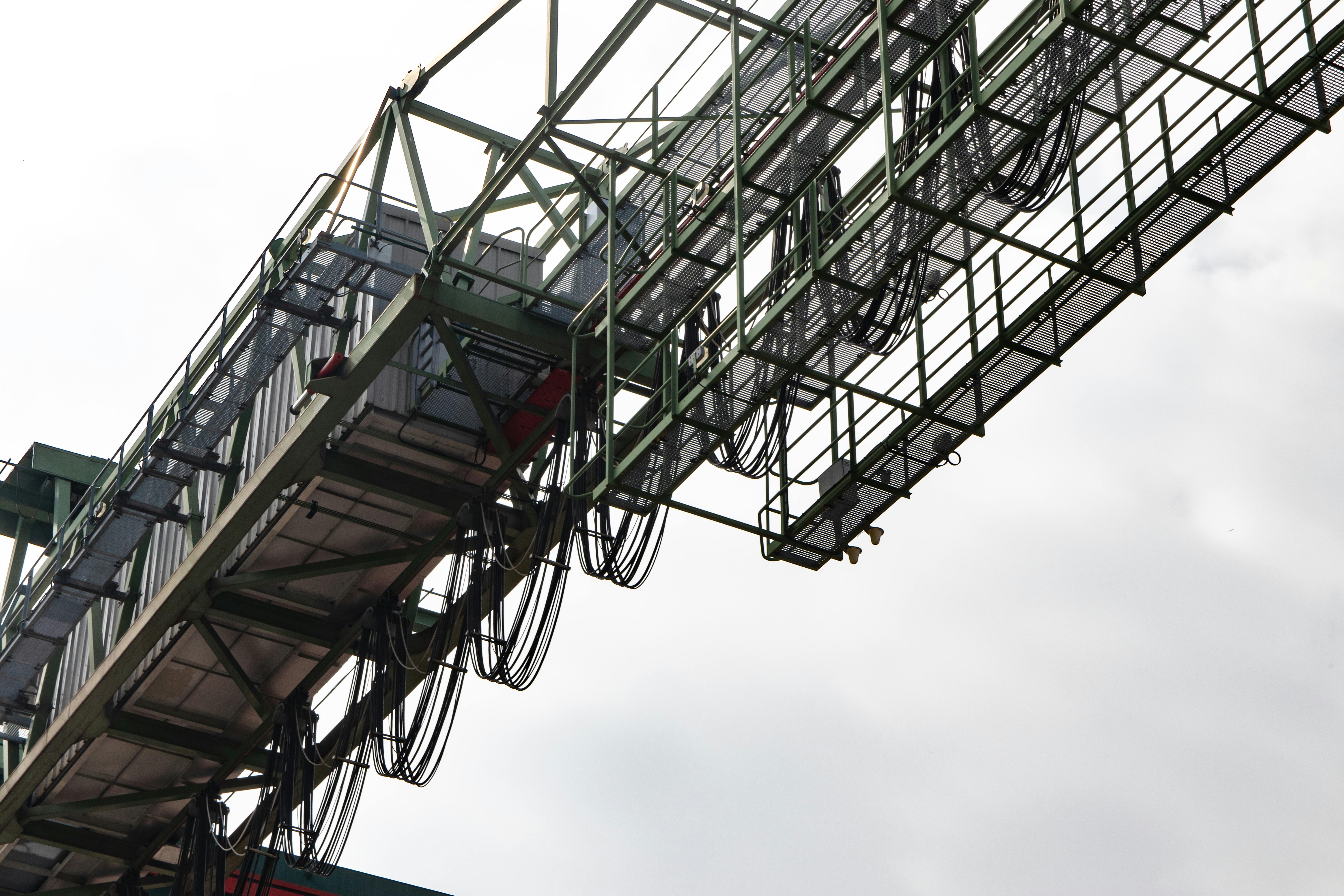 gratis Close-up van een industriële metalen constructie met zichtbare kabels tegen een heldere hemel. Stockfoto