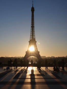 Captivating silhouette of the Eiffel Tower at sunrise with people in Paris, France.