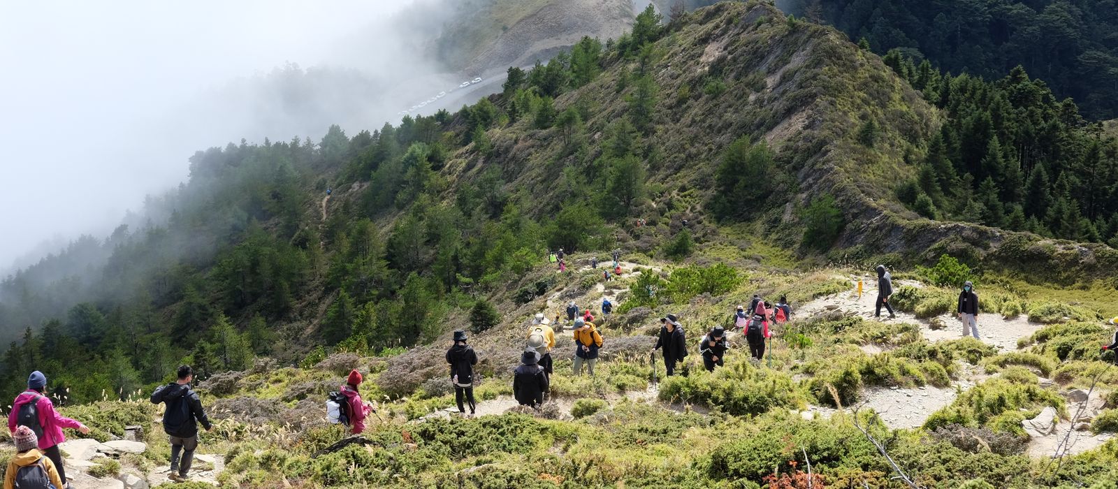 A group of hikers descends a foggy mountain trail in scenic Nantou County, Taiwan.