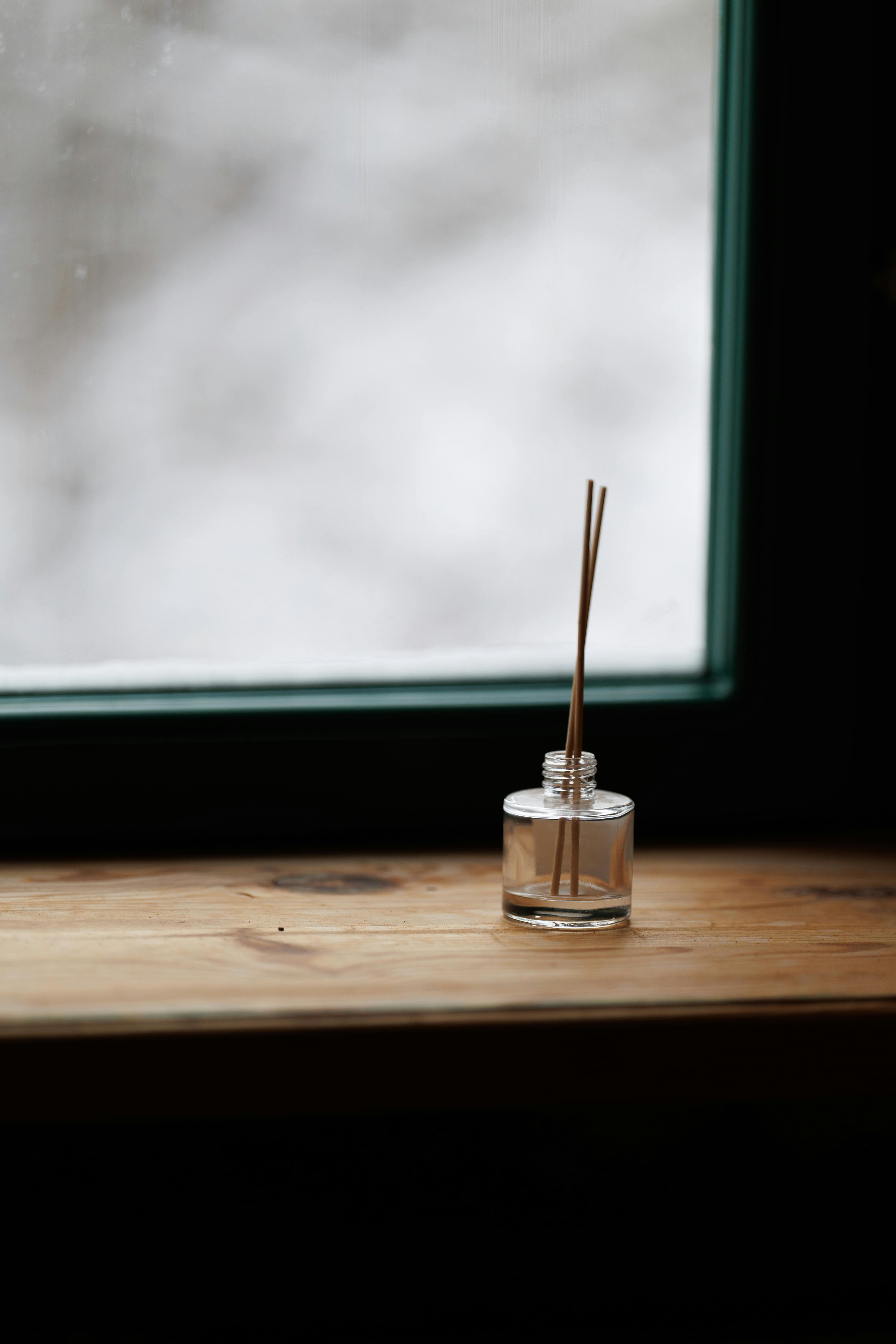 Kostenlos Ein minimalistischer Schilfdiffusor auf einer hölzernen Fensterbank mit sanftem, natürlichem Licht. Stock-Foto