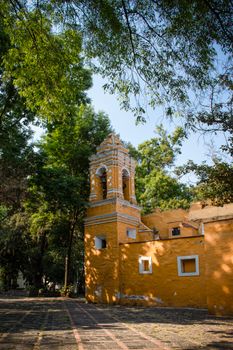 Beautiful colonial-era church surrounded by lush trees in Coyoacán, Ciudad de Mexico.