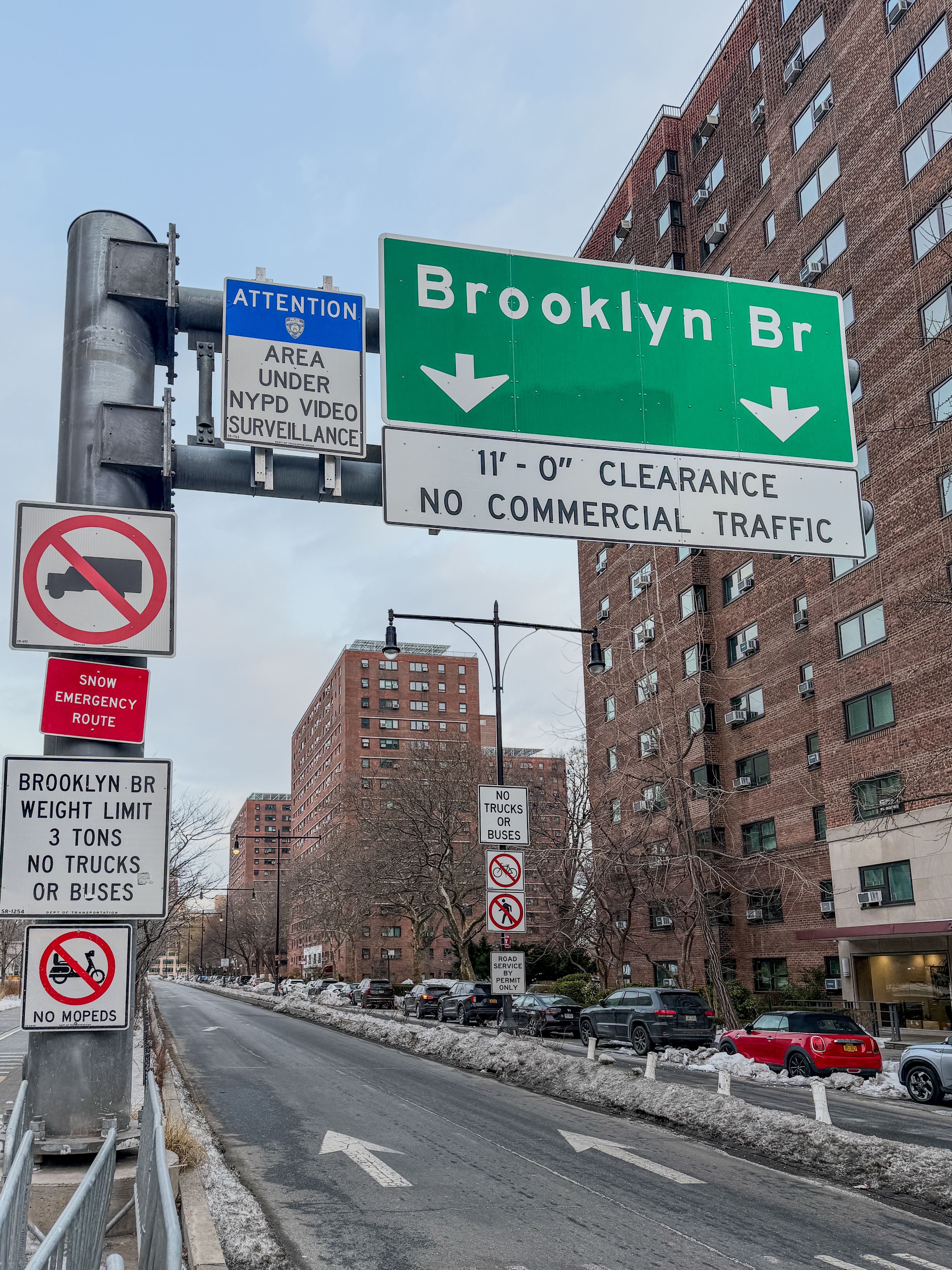 Traffic signs leading to the Brooklyn Bridge in New York City, highlighting clearance and restrictions.