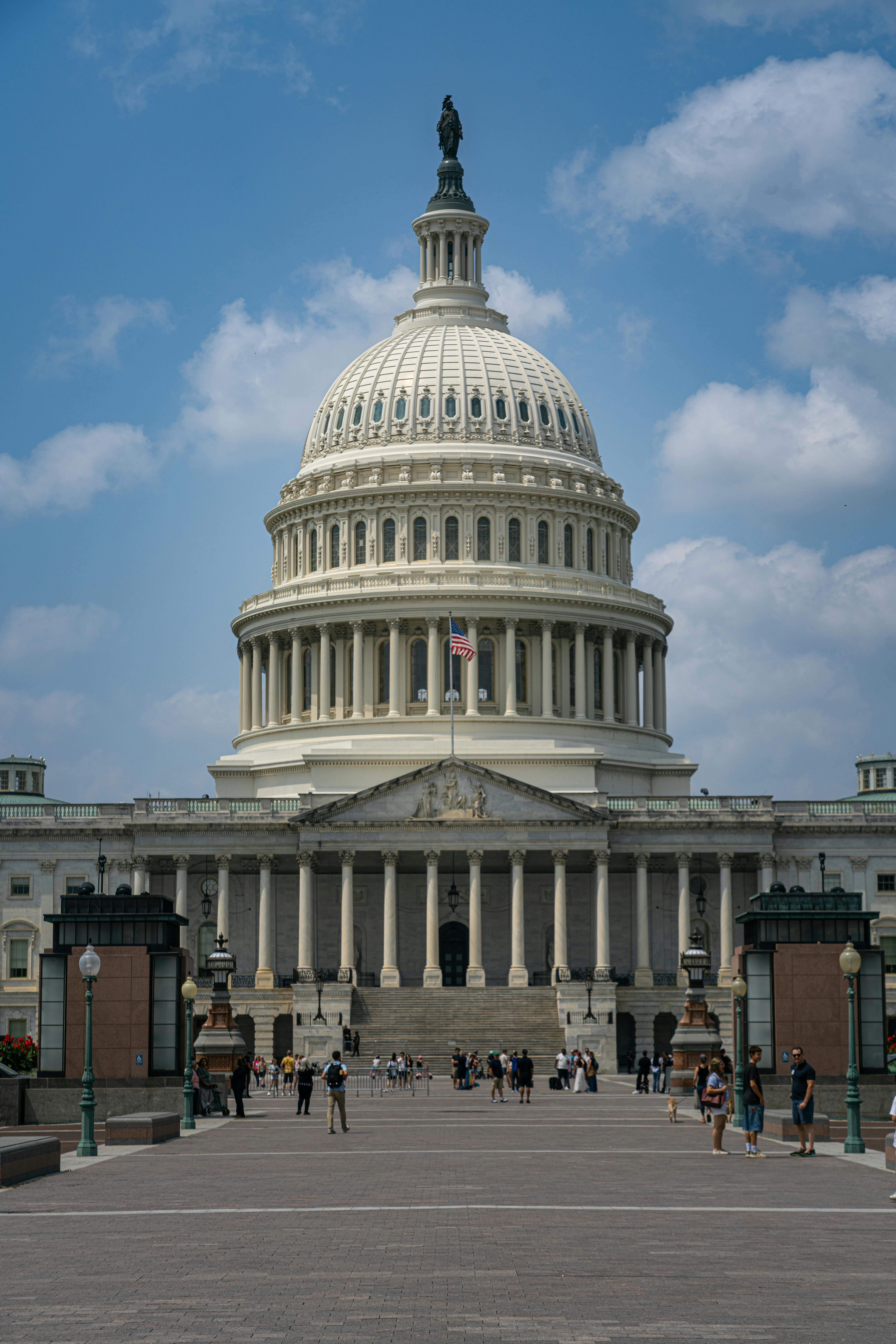 Iconic US Capitol building with people and cloudy sky in Washington, D.C.