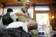 Barber giving a traditional hot towel shave in Buenos Aires barbershop.