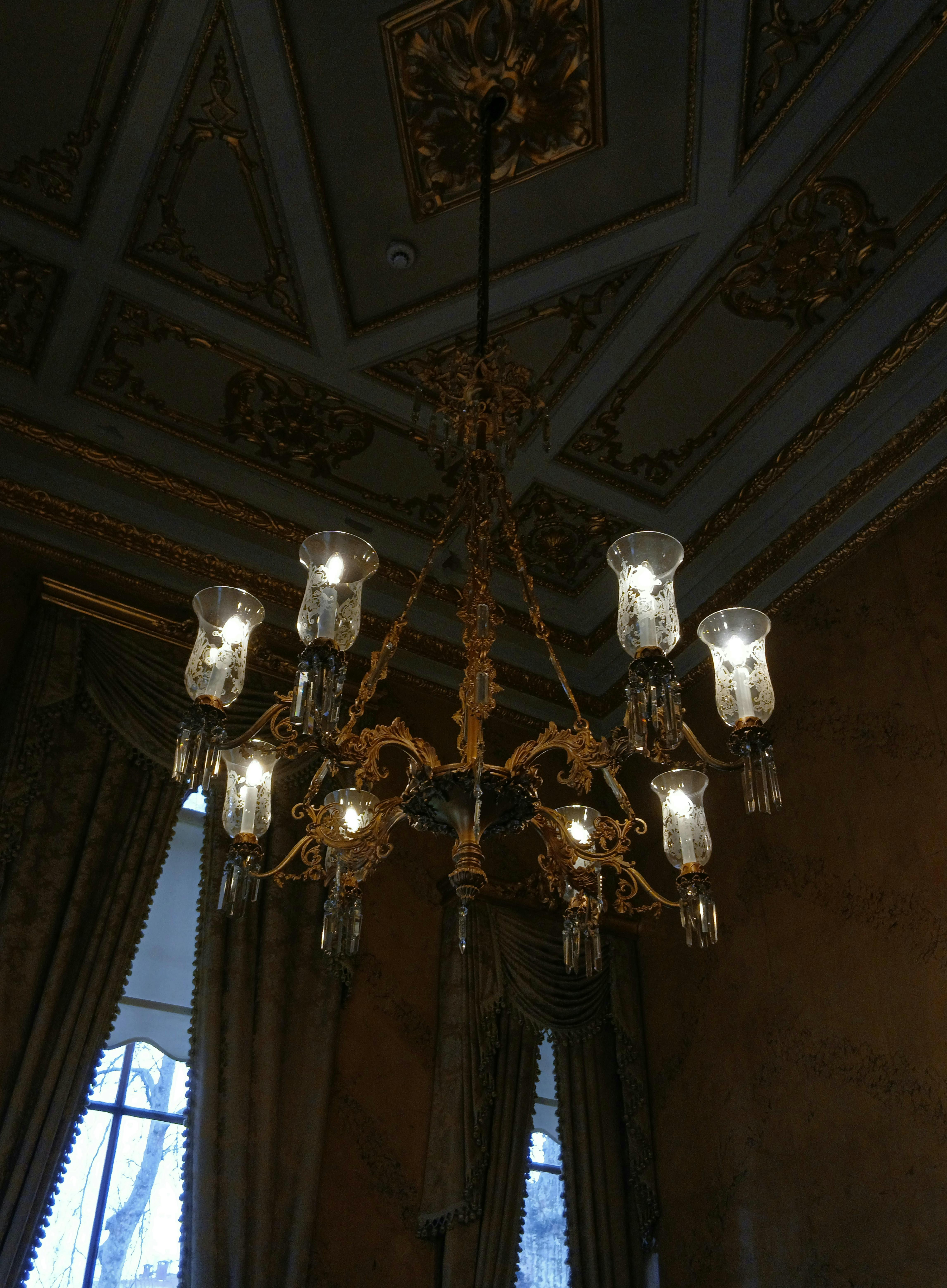 gratis Een weelderige kroonluchter hangt aan een rijkelijk versierd plafond in een klassiek interieur. Stockfoto