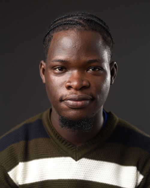 Free Close-up portrait of a young man wearing a striped sweater against a dark background. Stock Photo