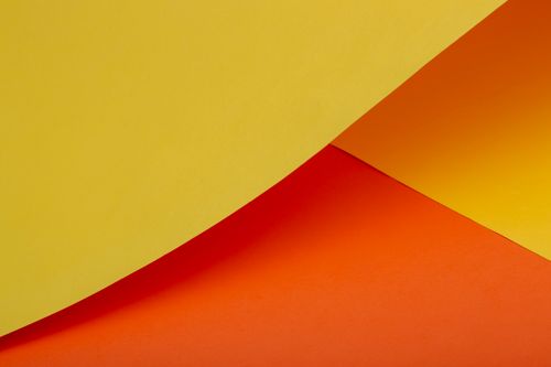 Free A vibrant abstract composition featuring curved yellow and orange paper, ideal for creative backgrounds. Stock Photo
