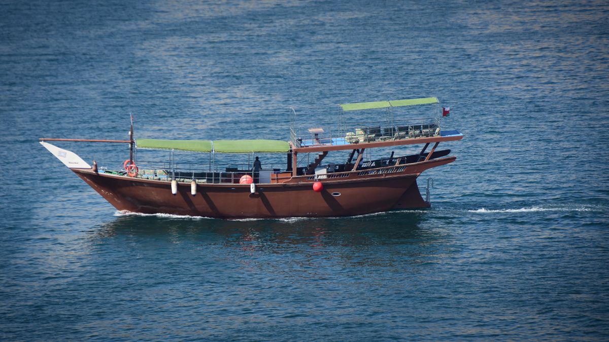 Traditional wooden dhow on the clear water of the Musandam fjords