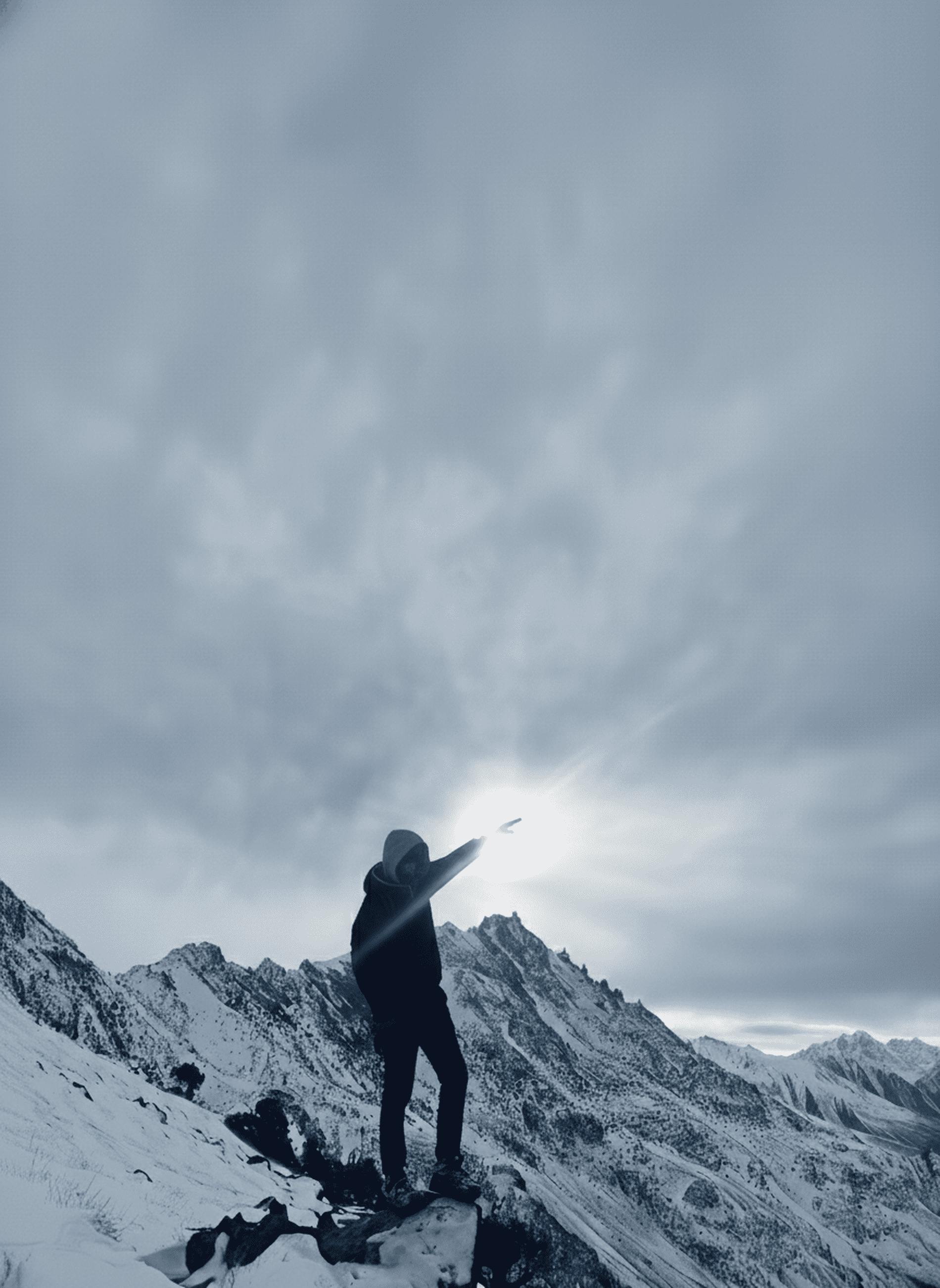 Gratis Un escursionista solitario si erge trionfante su una cima innevata sotto un cielo spettacolare a Garelt. Foto a disposizione