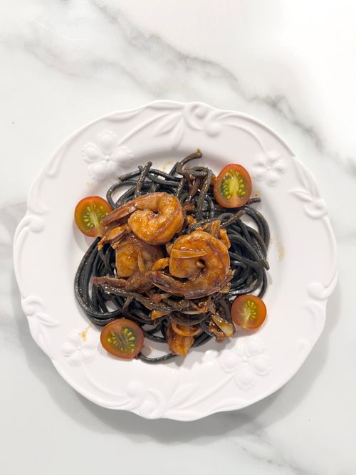 Free Savor the elegance of black pasta topped with succulent shrimp and fresh cherry tomatoes. Stock Photo