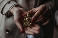 特写镜头展示了一只握着华丽金色香水瓶的手，凸显其复杂的设计