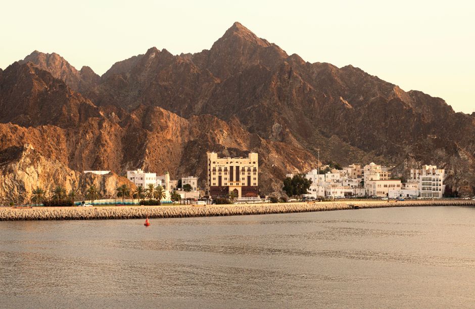 Picturesque view of Muscat's coastline with mountains and traditional architecture