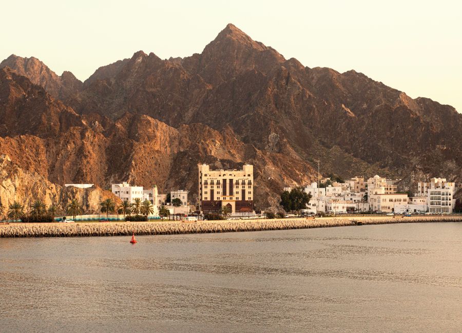 Picturesque view of Muscat's coastline with mountains and traditional architecture