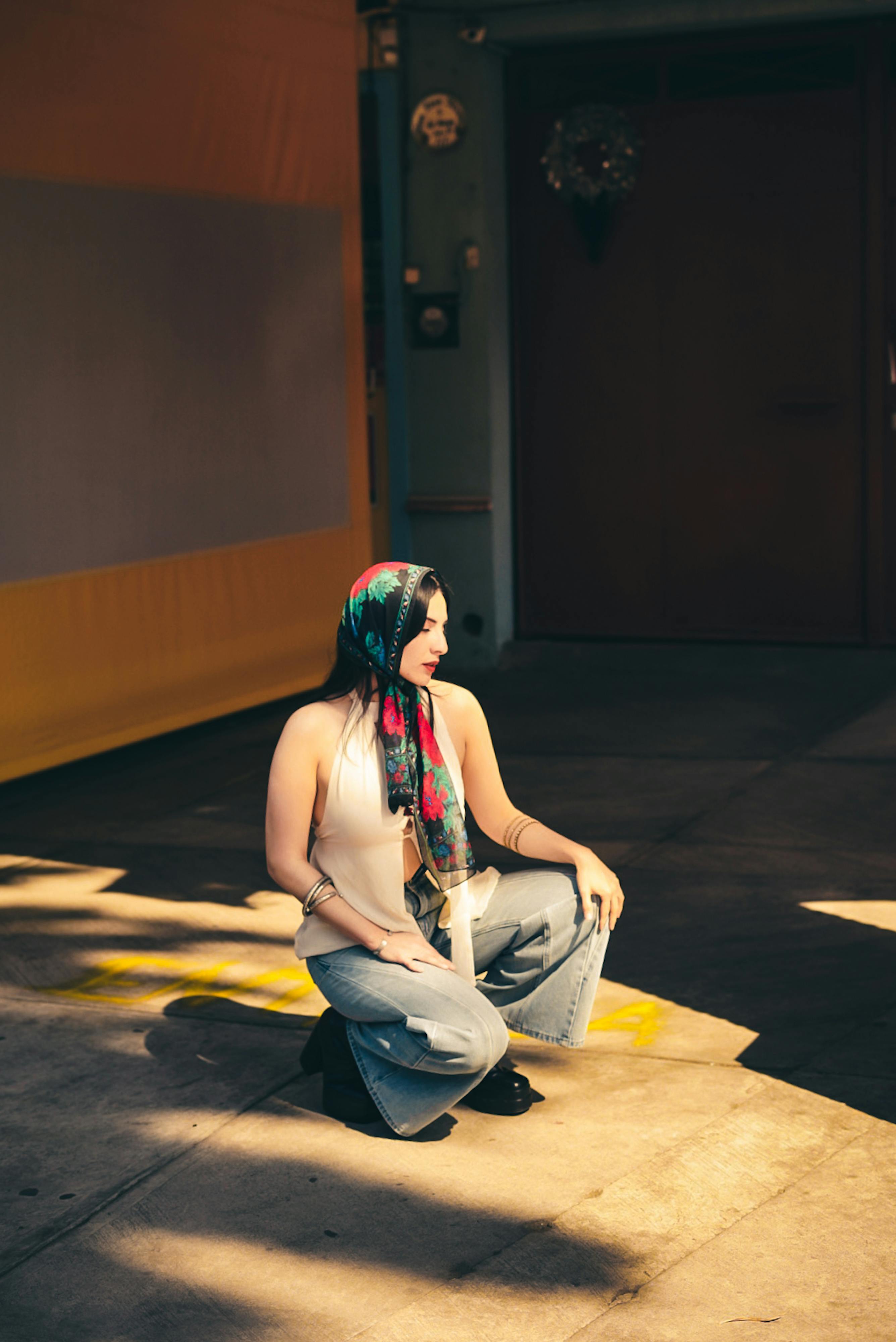 gratis Stijlvolle vrouw met hoofddoek poseert in een stedelijke omgeving, warm licht. Stockfoto