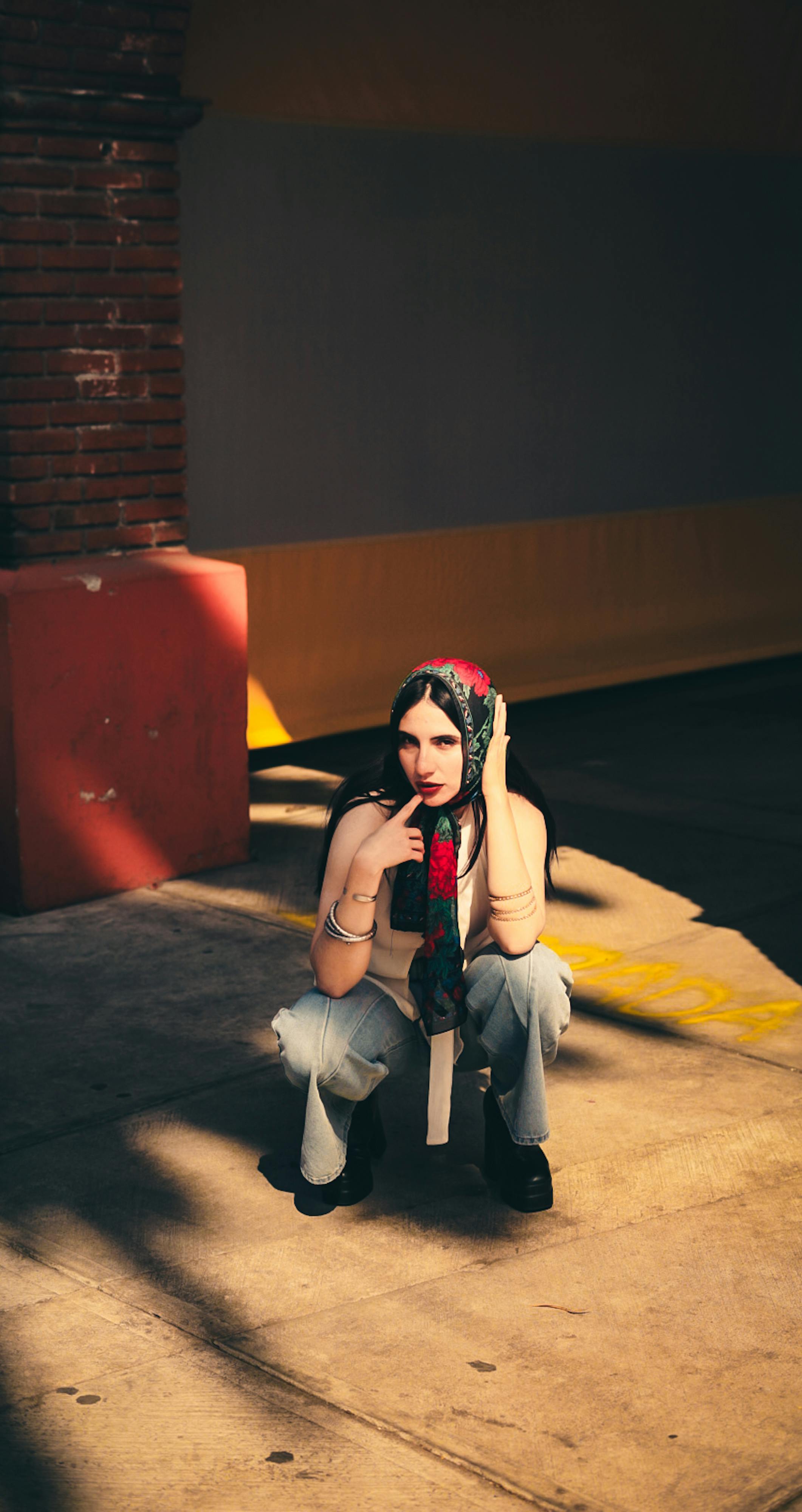 Miễn phí Một phụ nữ trẻ tạo dáng trong trang phục sành điệu và khăn trùm đầu, được chiếu sáng bởi ánh nắng chiều tà trong khung cảnh đô thị. Ảnh lưu trữ