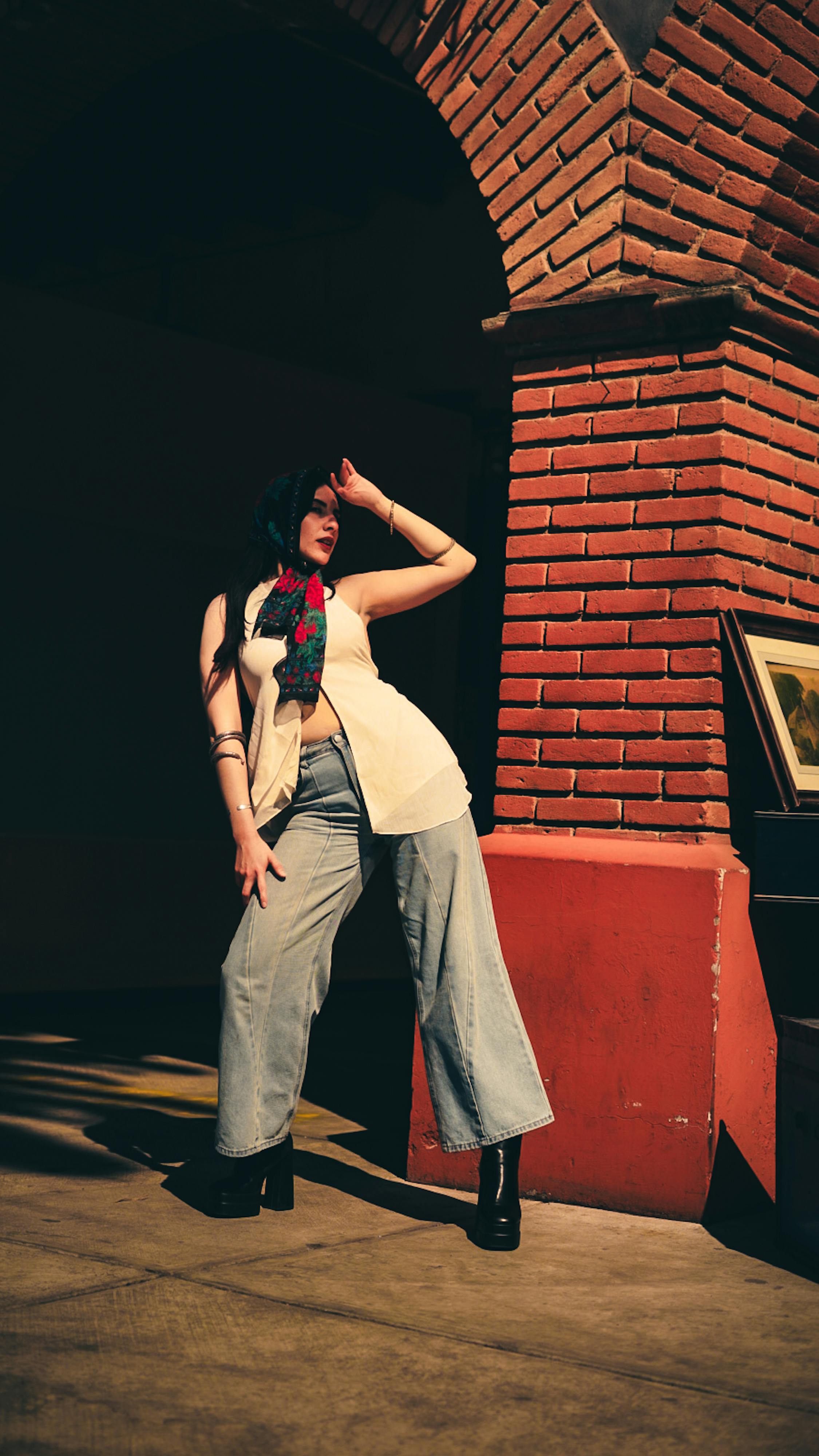 bezplatná Stylová žena sebevědomě pózuje proti cihlovému oblouku v městském prostředí. Základová fotografie