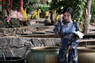 Elegant Woman in Traditional Dress Holding Flower Outdoors