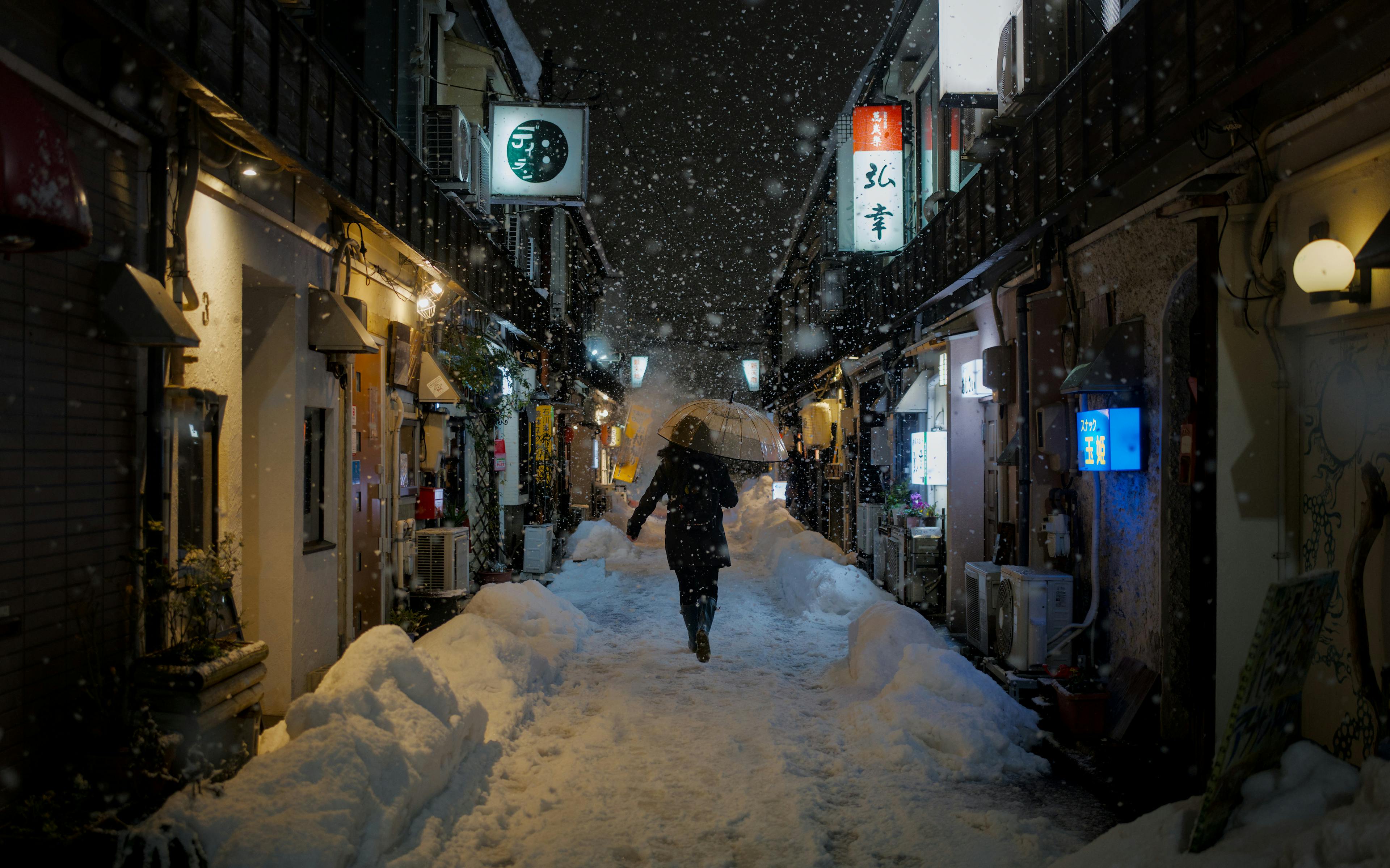 Kostenlos Eine einsame Gestalt geht nachts durch eine verschneite Gasse in Kanazawa, Japan. Stock-Foto