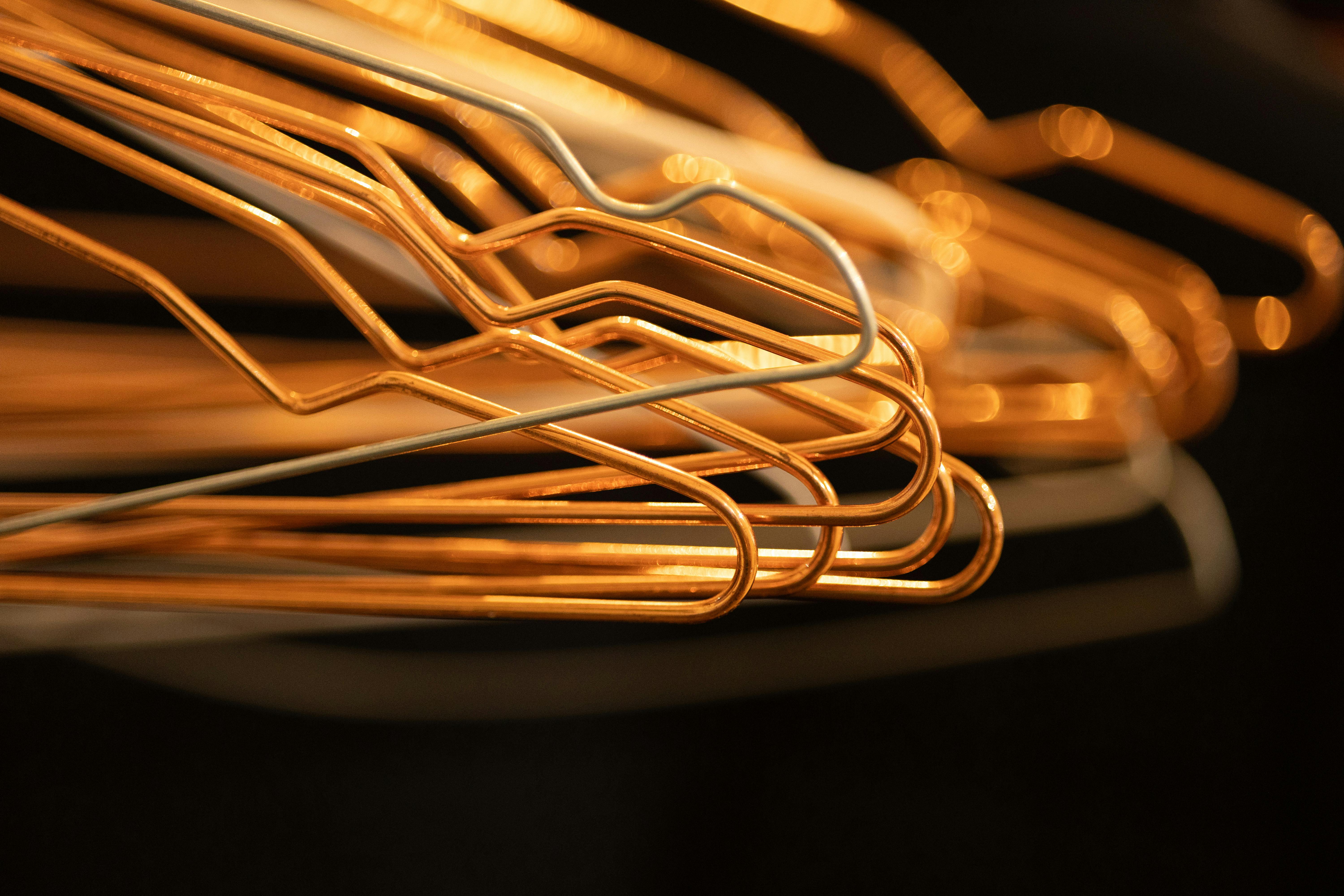 Miễn phí Hình ảnh cận cảnh trừu tượng của những chiếc móc treo quần áo bằng dây thép xếp chồng lên nhau dưới ánh sáng ấm áp. Ảnh lưu trữ