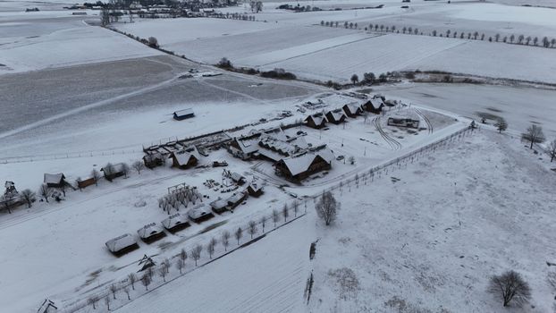Aerial view of a snow-covered village landscape in Poland during winter, showcasing traditional wooden houses.