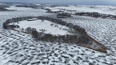 Aerial photo of a snow-covered island surrounded by a frozen lake during winter.